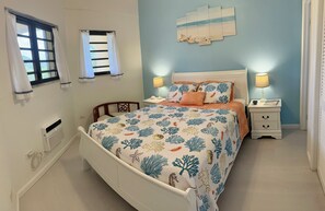 A bedroom with a bed, nightstands, a window with curtains, a wall-mounted artwork, and a bedside lamp.