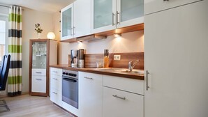 Eine moderne Küche mit weißen Schränken, einer Holz Arbeitsplatte, einem eingebauten Backofen und einer Kaffeemaschine.