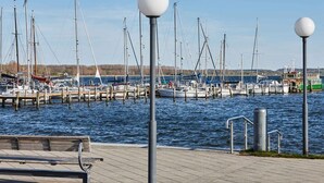 Ein Yachthafen mit mehreren Booten, die an hölzernen Stegen festgemacht sind, eine Bank und zwei runde Laternen auf Pfählen.
