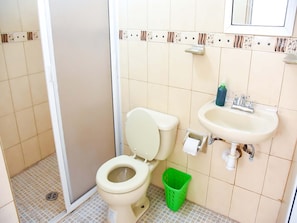 A small bathroom with a toilet, sink, and green trash bin. - Hospedaje Casa de la Campana Rotamundos (Guanajuato)