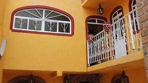 A multi-story building with yellow walls, arched windows, and a balcony with white railings. - Hospedaje Casa de la Campana Rotamundos (Guanajuato)