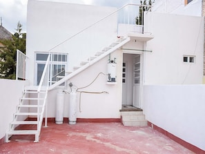 A white building with a staircase leading to a balcony, a water heater, and a small window. - Hospedaje Casa de la Campana Rotamundos (Guanajuato)