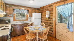 Una cocina compacta con muebles de madera, un refrigerador blanco, un microondas y una mesa de comedor con cuatro sillas.
