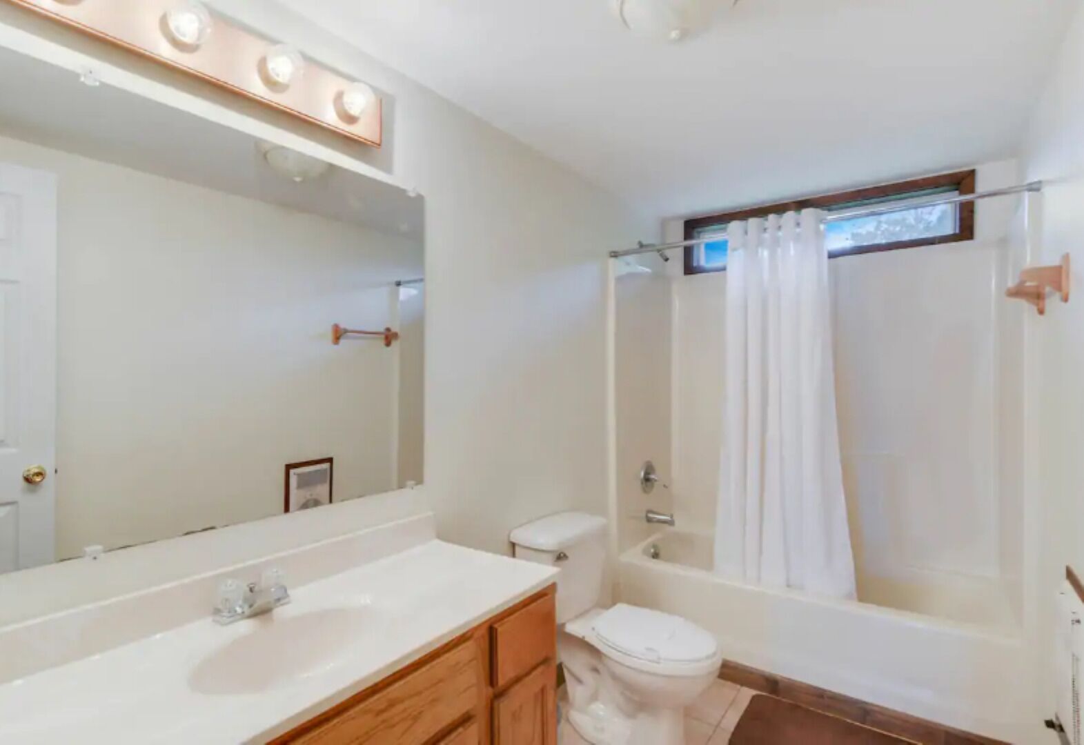 A bathroom with a white sink, vanity, toilet, and bathtub.