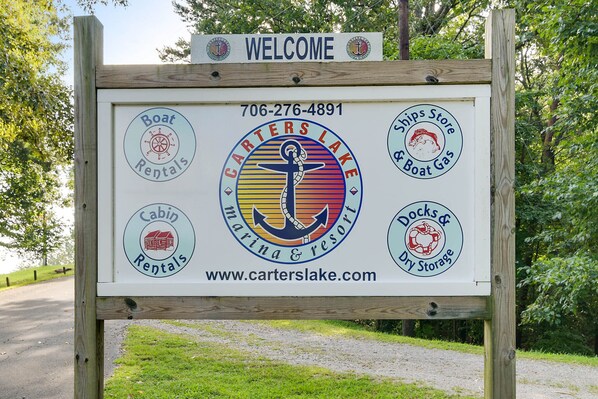 Panneau d'accueil de Carters Lake Marina & Resort, indiquant les coordonnées et les services proposés, tels que la location de bateaux, la location de chalets et le stockage à sec.