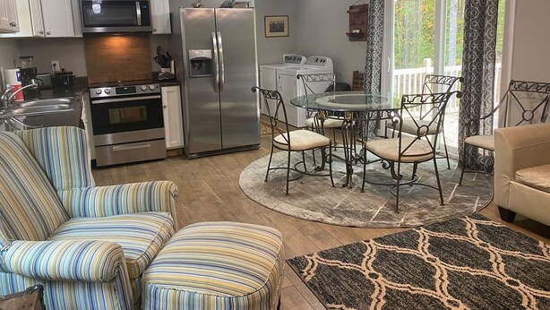 A modern kitchen with stainless steel appliances, a dining area with a glass table and metal chairs, and a cozy seating area with striped chairs. - 2Bedroom, 1.5Bath Cottage at Beautiful Wood Creek Lake,  Near Wood creek Marina. (London)