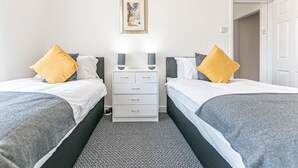 Una habitació doble amb dos llits, cadascun amb un coixí, una taula de nit amb una làmpada i un quadre encimbellat a la paret.