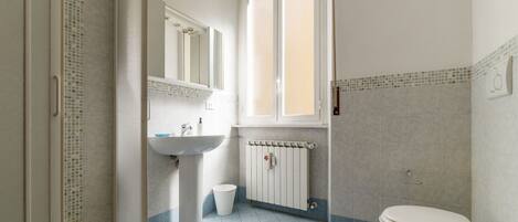 A bathroom with a sink, toilet, and shower area.