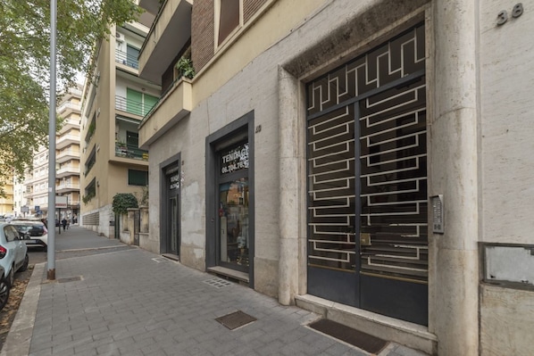 Un bâtiment doté d’un grand portail en métal, d’une adresse clairement visible et d’un trottoir pavé.