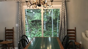 A dining area with a large table, chairs, a chandelier, and a view of a forest through a glass door. - Peaceful 2Bedroom, 1.5Bath Cottage near Wood Creek Boat Dock (London)