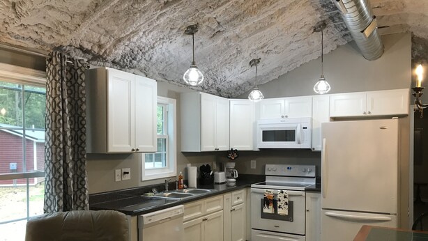 A modern kitchen with white cabinets, a stainless steel sink, a microwave, a stove, and a refrigerator. There is a window with a view of the outdoors, and a chair is visible in the foreground. - Peaceful 2Bedroom, 1.5Bath Cottage near Wood Creek Boat Dock (London)