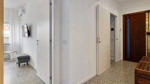 A modern interior with white walls, a grey bench, and a wooden door. - GuestHost - ⋆Inner City Suite⋆ a stone's throw from Piazza S.Oronzo! (Lecce)