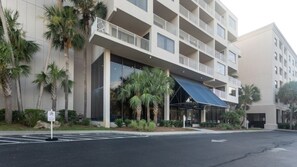 A hotel with a modern design, featuring a glass facade and a blue awning.