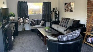 Een woonkamer met een bank, fauteuil, salontafel en een tv-meubel.
