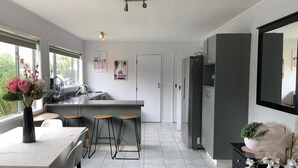 Een moderne keuken met een centraal eiland, barstoelen en een eettafel met stoelen.
