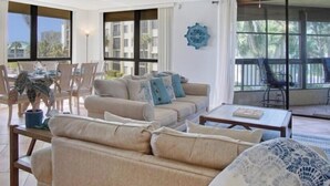 A spacious living room with a sofa set, a coffee table, and a dining area with chairs. - SS 4224 2/2 Garden View Condo - Paradise Vacation Rental in Ocean Village (Fort Pierce)