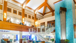 Experience the grandeur of our hotel lobby, featuring a high ceiling, central staircase, and comfortable seating areas.