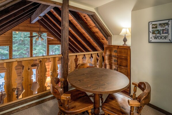 A wooden dining area with a round table and chairs, a wooden cabinet, and a ceiling fan.