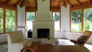 A cozy room with a fireplace, wooden ceiling, and large windows offering a view of greenery. - San Nicolás Rotamundos (San Cristóbal de las Casas)