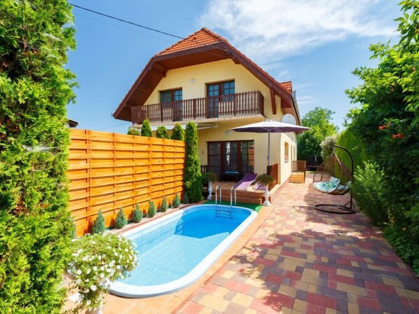 A two-story house with a swimming pool, a wooden fence, and a garden. - Vacation home Ilona by Interhome (Siofok)