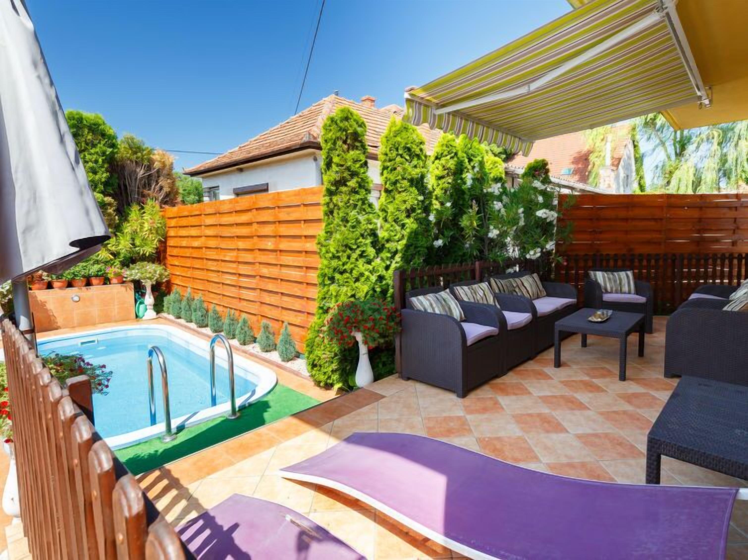 Un jardin avec une piscine, du mobilier d’extérieur et une pergola.