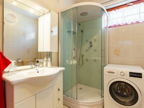 A bathroom with a glass-enclosed shower, a sink, and a washing machine. - Vacation home Ilona by Interhome (Siofok)