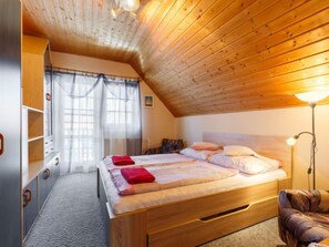 A cozy bedroom with a wooden ceiling, a bed with multiple pillows, a bedside lamp, and a wardrobe with a mirror. - Vacation home Ilona by Interhome (Siofok)