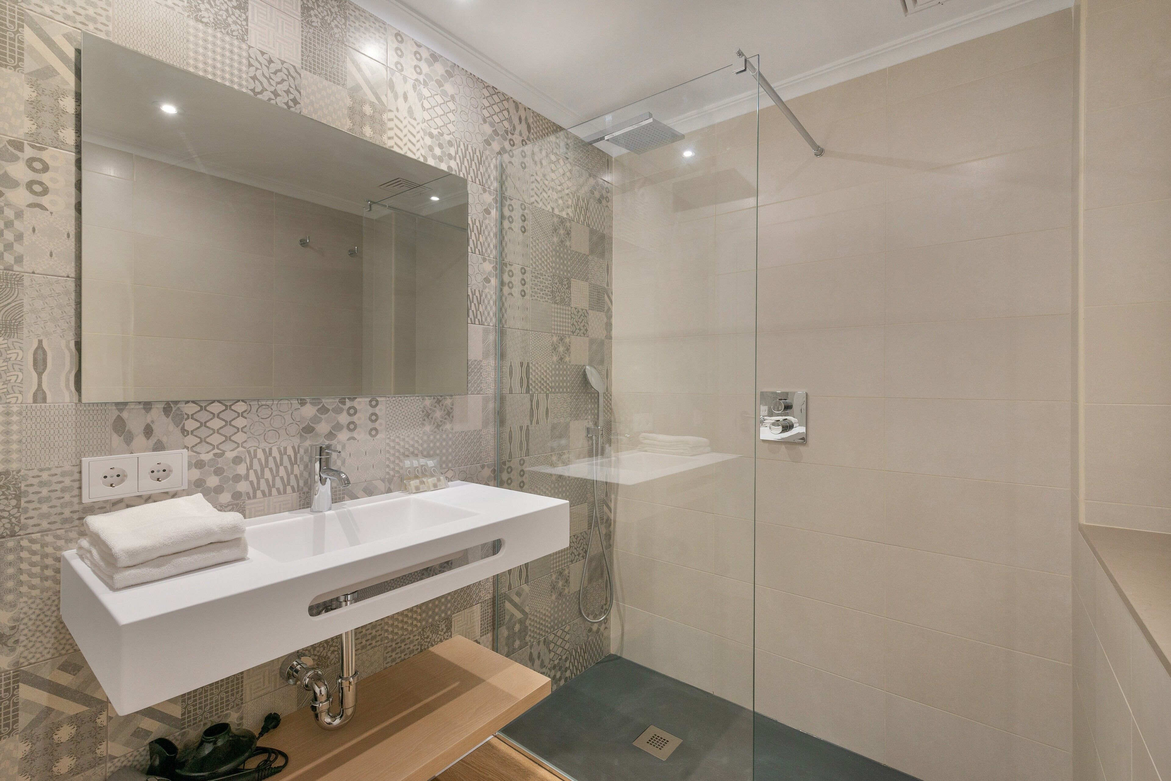 A modern bathroom with a white sink, mirror, and shower.