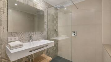A modern bathroom with a white sink, mirror, and shower.