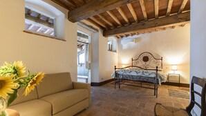 A bedroom with a bed, a sofa, a chair, and a vase with flowers.