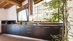 A kitchen with dark cabinets, a stainless steel range hood, and a window with a view of greenery.
