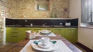 A kitchen with a stone wall, green cabinets, a wooden table, and a small window. - PICCIONAIA - country home with garden in the heart of Chianti - 2 persons (Montespertoli)