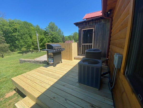 Une terrasse en bois équipée d’un barbecue et d’un grand climatiseur.