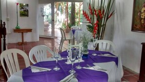 A dining area with a purple tablecloth, white chairs, and a glass vase with flowers. - Complete house with lush vegetation, hot water Jacuzzi for 12 people (Santagueda Palestina Caldas)