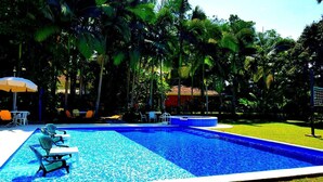 A swimming pool with lounge chairs and a table, surrounded by palm trees. - Complete house with lush vegetation, hot water Jacuzzi for 12 people (Santagueda Palestina Caldas)