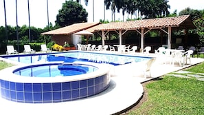 A swimming pool with a hot tub, surrounded by lounge chairs and a covered patio area.