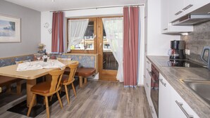 Un'accogliente zona pranzo con tavolo e sedie in legno, una panca e vista attraverso una porta vetrata.