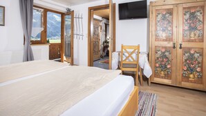 Una camera da letto con un letto, una sedia, una TV e un'armadio in legno decorato con motivi floreali.