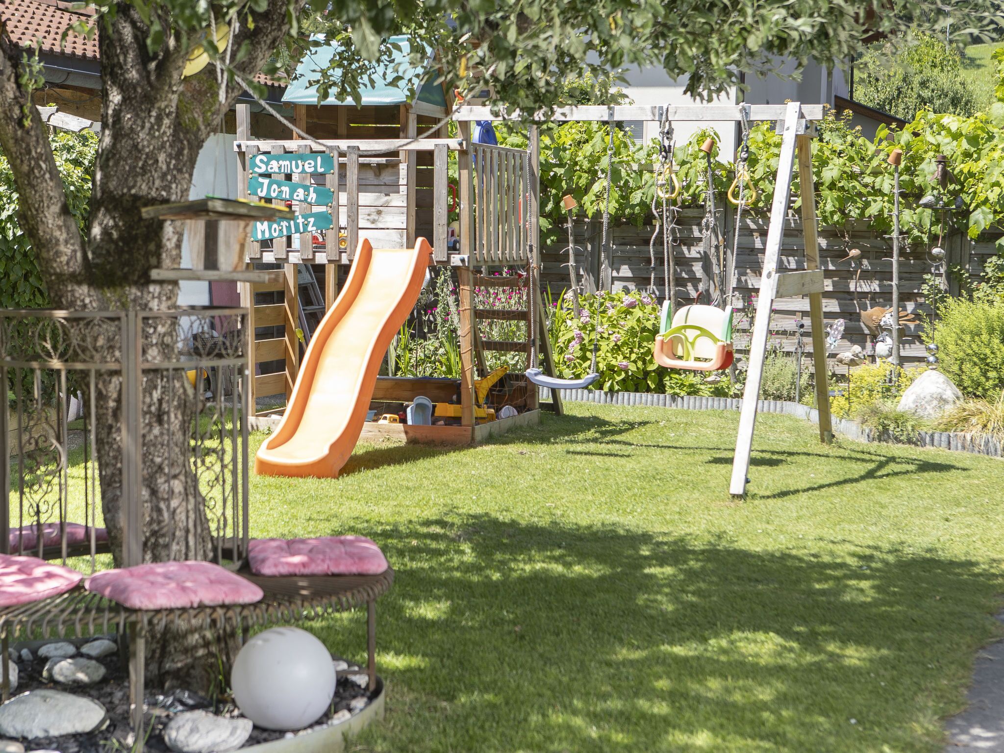 A playground with a slide, swings, and a wooden playhouse.