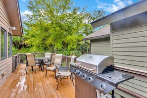A wooden deck with a grill and outdoor furniture.