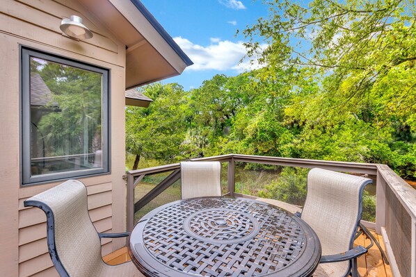 Une terrasse avec une table ronde et deux chaises, offrant une vue sur un paysage verdoyant et luxuriant.