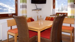Un espace repas comprenant une table, des chaises et un téléviseur fixé au mur.