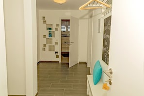 Un couloir doté d’un plancher en bois, une porte ornée d’un motif en forme de cœur et un mur sur lequel est accroché un panneau en forme de tableau noir.
