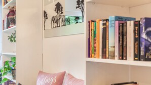 Een boekenplank met boeken, een teddybeer en een kunstwerk aan de muur.
