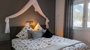 Een bed met hemel, kussens en een bedlampje.