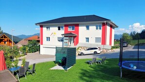 Un bâtiment à deux étages avec une façade rouge et blanche, un garage et une voiture garée devant.