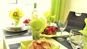 Une table à manger dressée avec des assiettes, des verres et des couverts, une bouteille et une plante décorative.