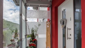 Une entrée moderne avec une porte en verre, un mur rouge et une pancarte d’accueil.
