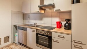 A modern kitchen with a stainless steel oven, a built-in dishwasher, and a red coffee maker on the countertop.