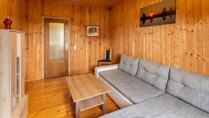 A wooden cabin interior with a sofa, a table, and a painting on the wall.